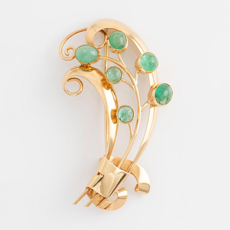 Brooch in 18K gold set with cabochon-cut emeralds.