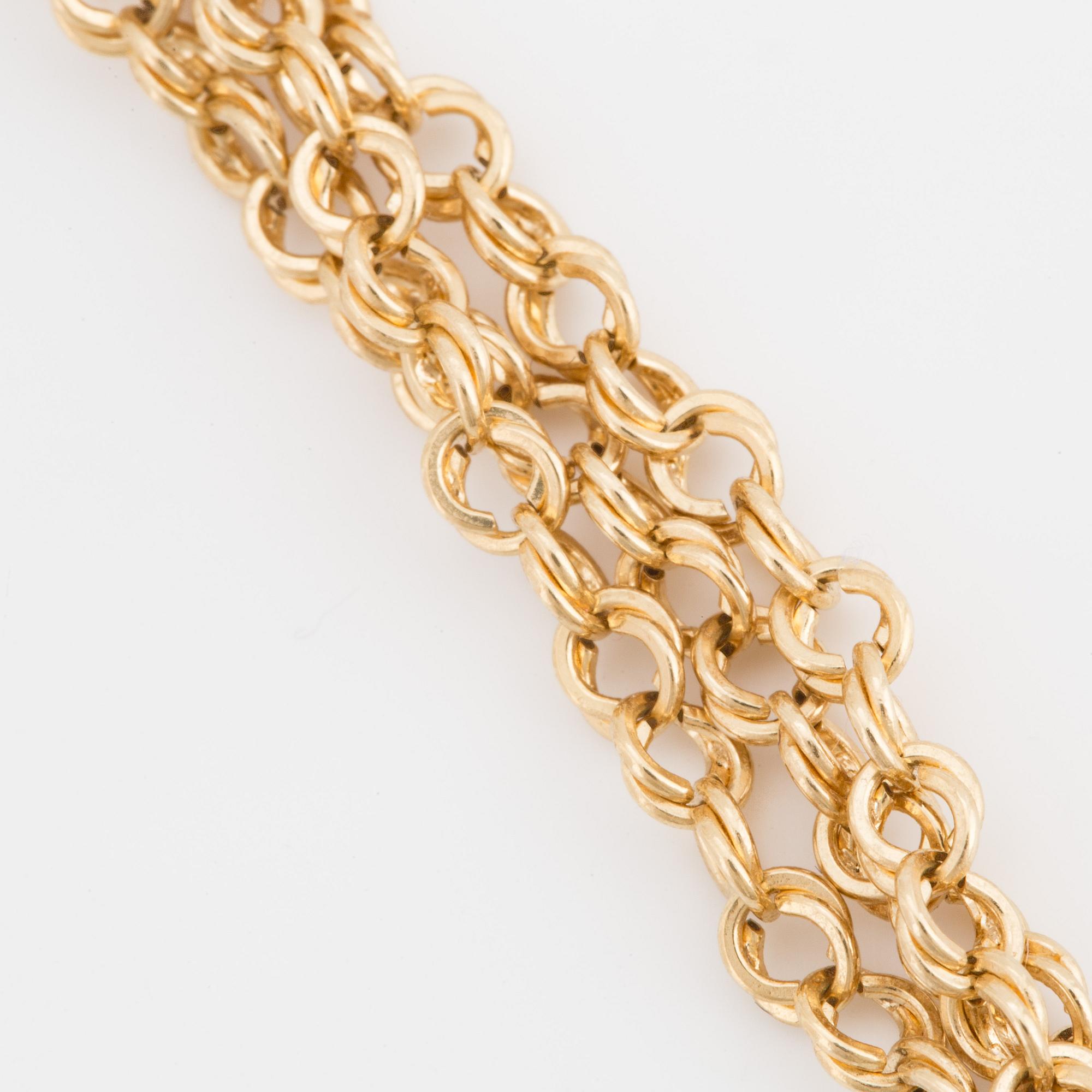 A three stranded chain necklace with a pendant in the shape of a flower ...