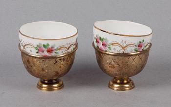 KOPPAR MED HÅLLARE, ett par, porslin resp silver, Ryssland resp Turkiet. Tidigt 1900-tal.