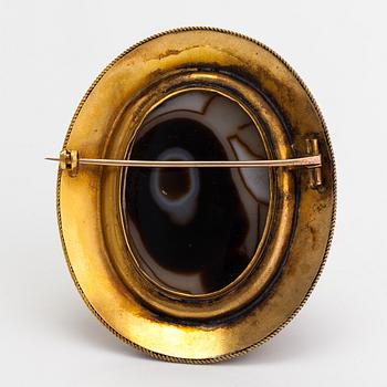 An 18K gold brooch with an onyx cameo and rubies.