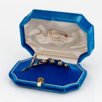 A brooch in 14K gold and silver set with old-cut diamonds, in the shape of a lily-of-the valley twig.
