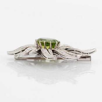 An 18K white gold brooch set with a faceted peridot and eight-cut diamonds.