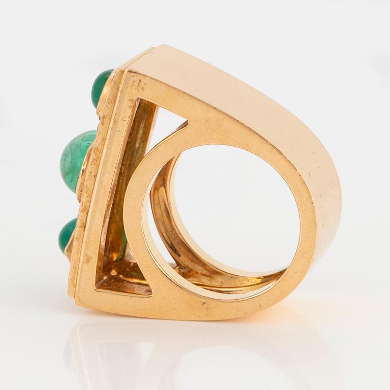 An 18K gold ring set with cabochon-cut emeralds and round brilliant-cut diamonds.