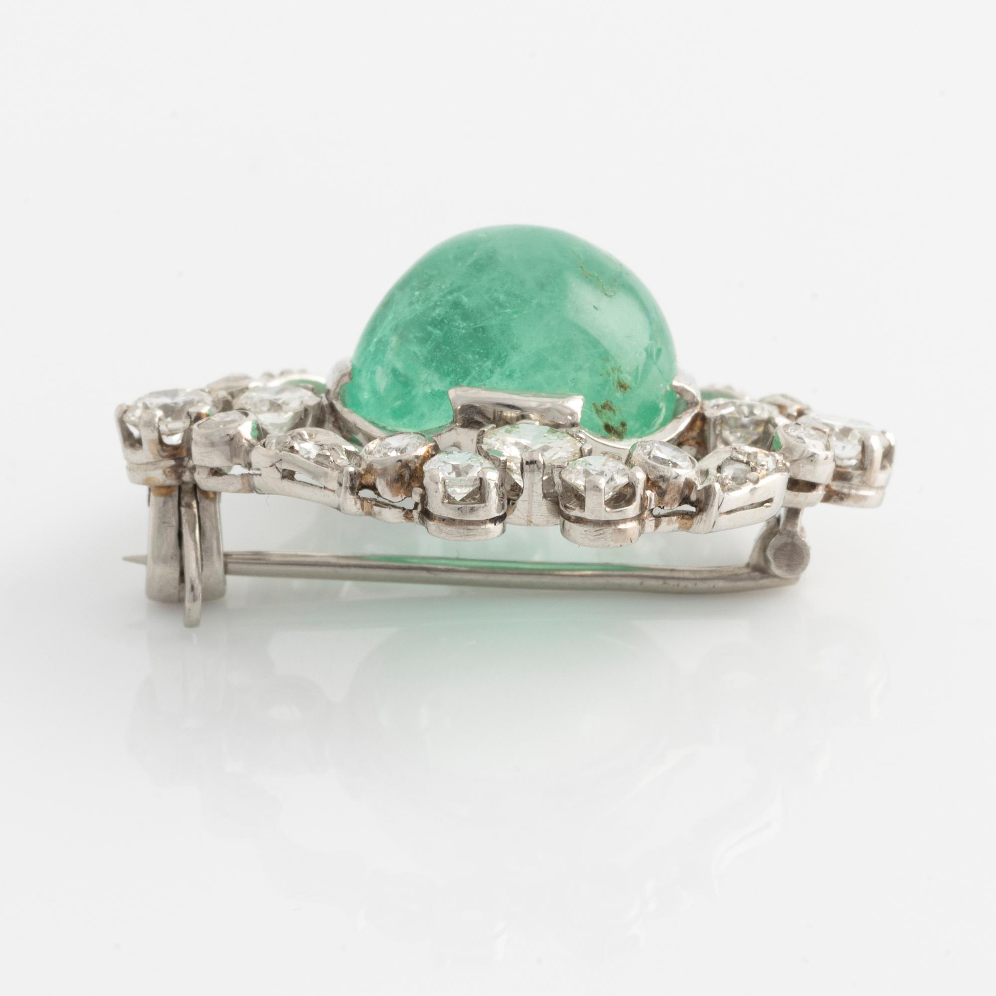 A platinum brooch with a cabochon-cut emerald.