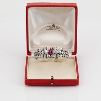 An 18K white gold bangle set with a cabochon-cut ruby and old-cut diamonds.