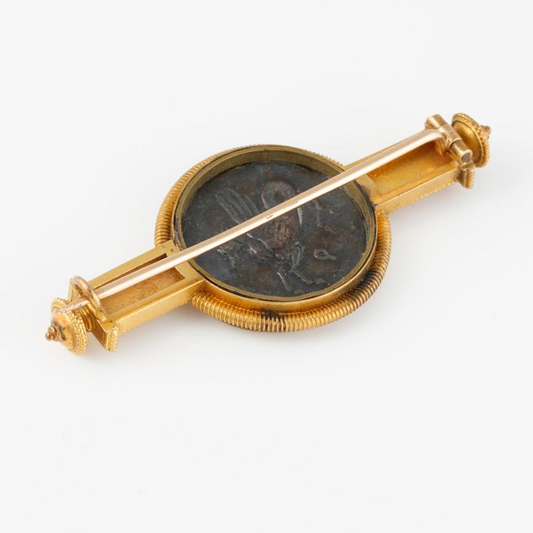 BROSCH, mynt infattat i låghaltigt guld.