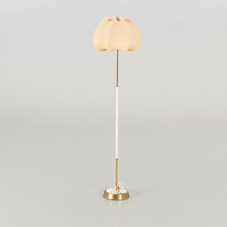 A brass floor light with white fabric lamp-shade.