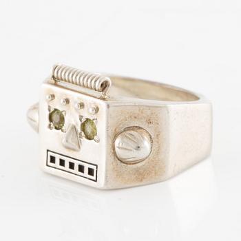 Maria Nilsdotter ring i form av ett robothuvud, sterlingsilver och gröna ögon.