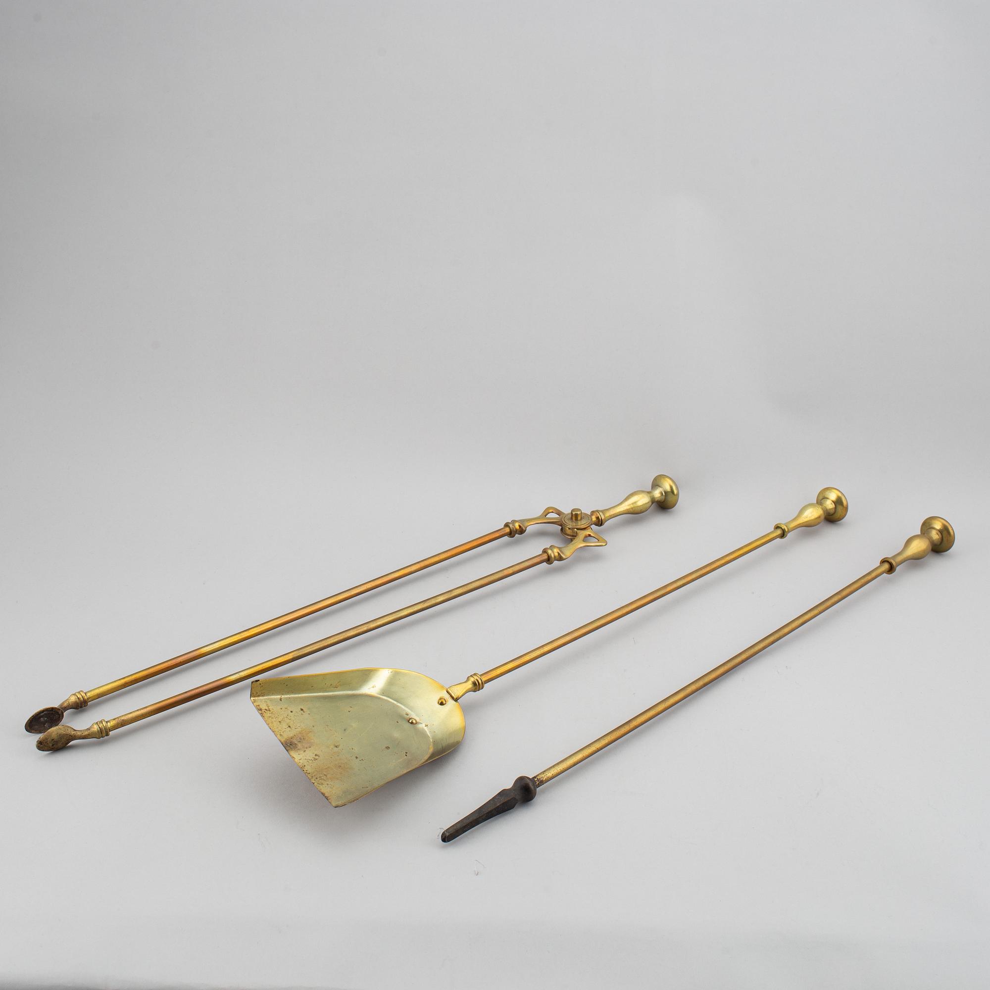 A pair of brass fire dogs and a brass fireplace poker set.