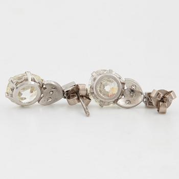 A pair of platinum earrings set with cushion formed old-cut diamonds with a total weight of ca 6.00 cts quality ca L/M v.