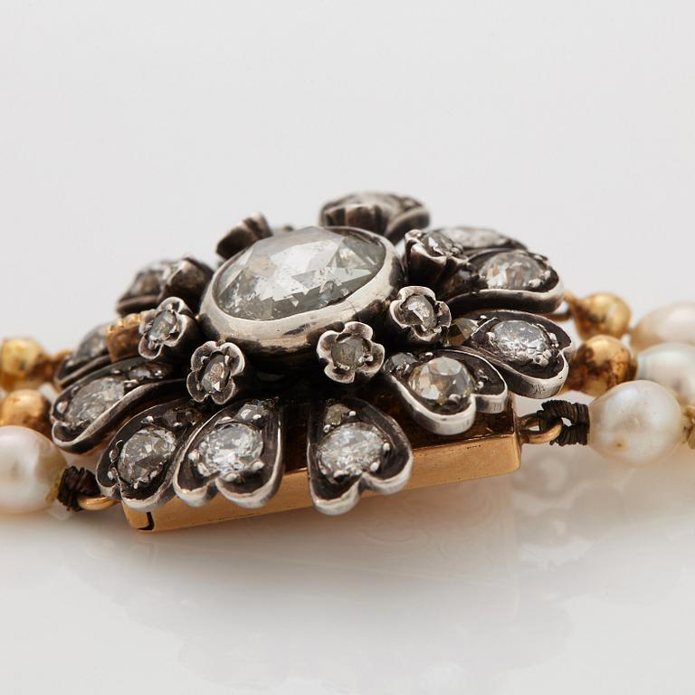 A three strand cultured pearl necklace with a clasp in 18K gold and silver set with rose- and old-cut diamonds.