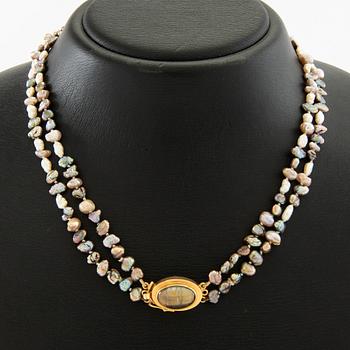 Necklace of cultured pearls with a clasp of 18K gold and cabochon-cut likely tourmaline.