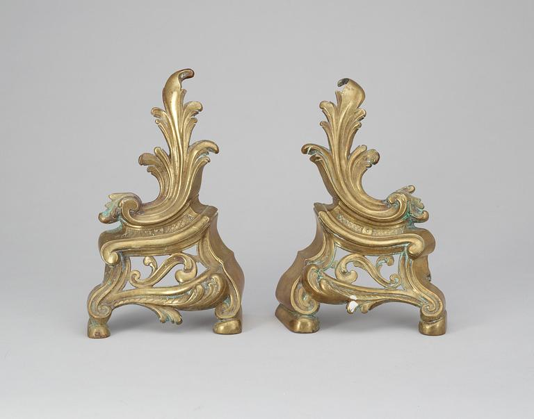 A pair of brass fire dogs. Rococo style.