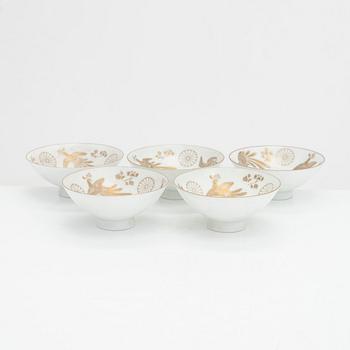 Five porcelain sake cups and a papier maché doll, Japan first half of the 20th century.