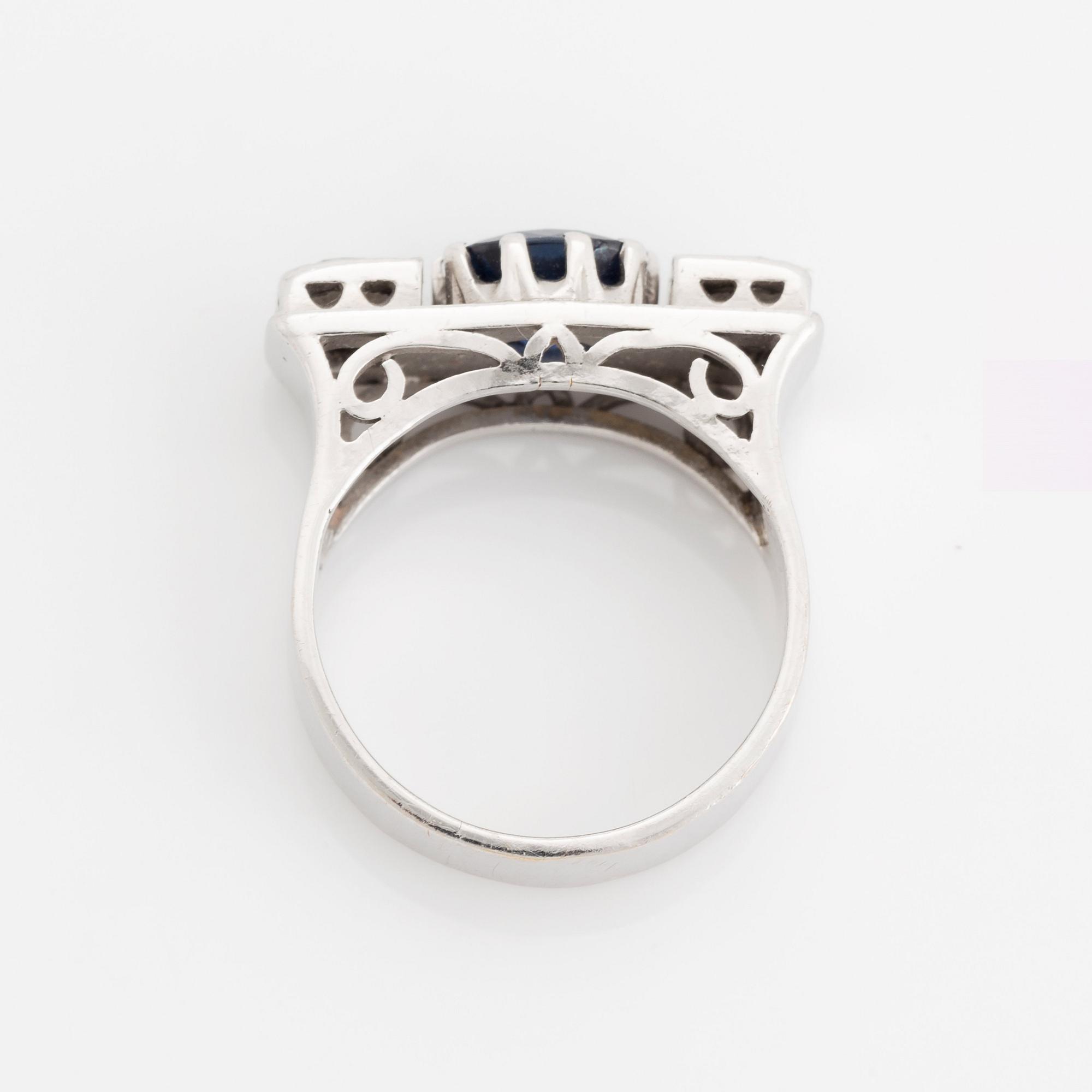 An 18K white gold ring set with a faceted sapphire, possibly synthetic, and round brilliant-cut diamonds.