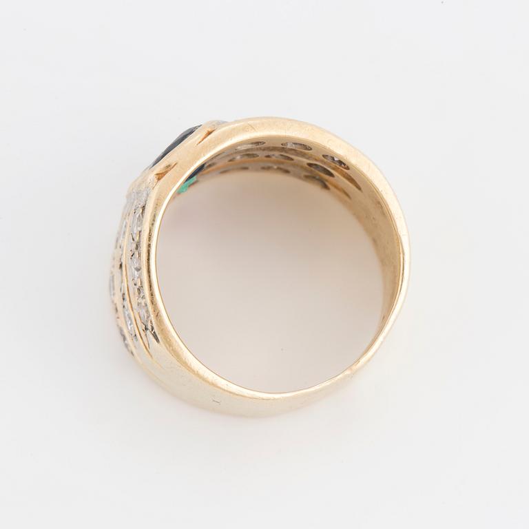 An oval cut ruby, sapphire and emerald ring, surrounded by brilliant cut diamonds.