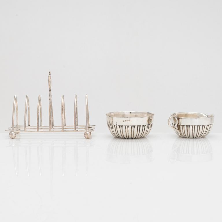 Sterling salt cellar, sugar bowl and creamer, Scotland and Sheffield; silver tea strainer, Turku, and plated toast rack.