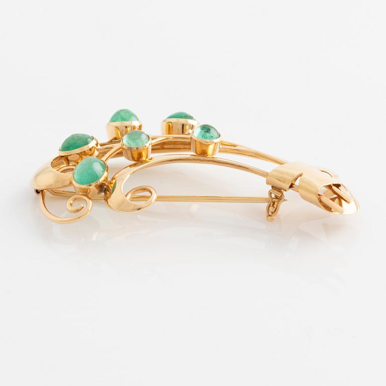 Brooch in 18K gold set with cabochon-cut emeralds.