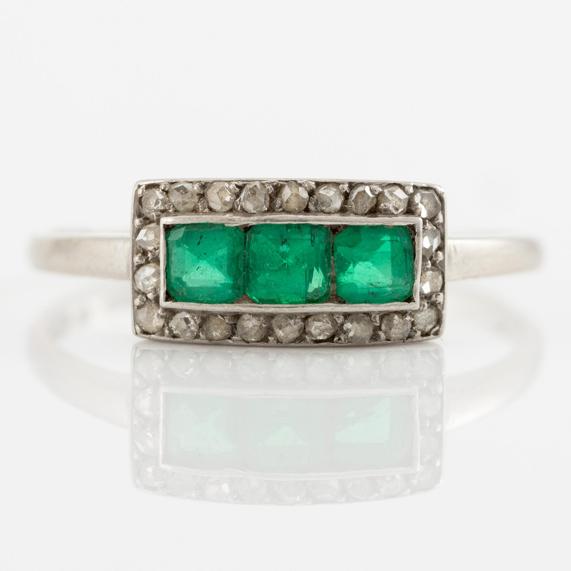 Ring in platinum set with step-cut emeralds and rose-cut diamonds.