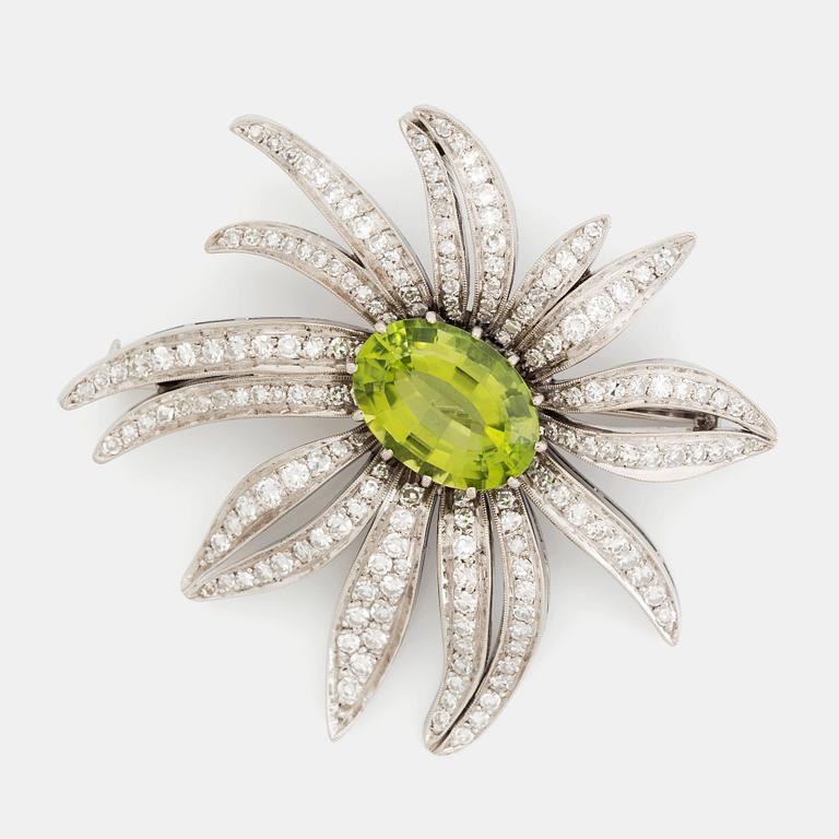 An 18K white gold brooch set with a faceted peridot and eight-cut diamonds.