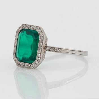 A platinum ring set with a Colombian step-cut emerald and old-cut diamonds in a fitted case from Cartier.