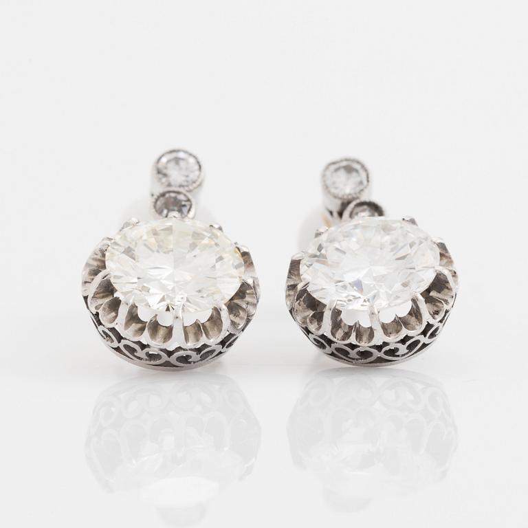 A pair of platinum earrings set with round brilliant- and old-cut diamonds.