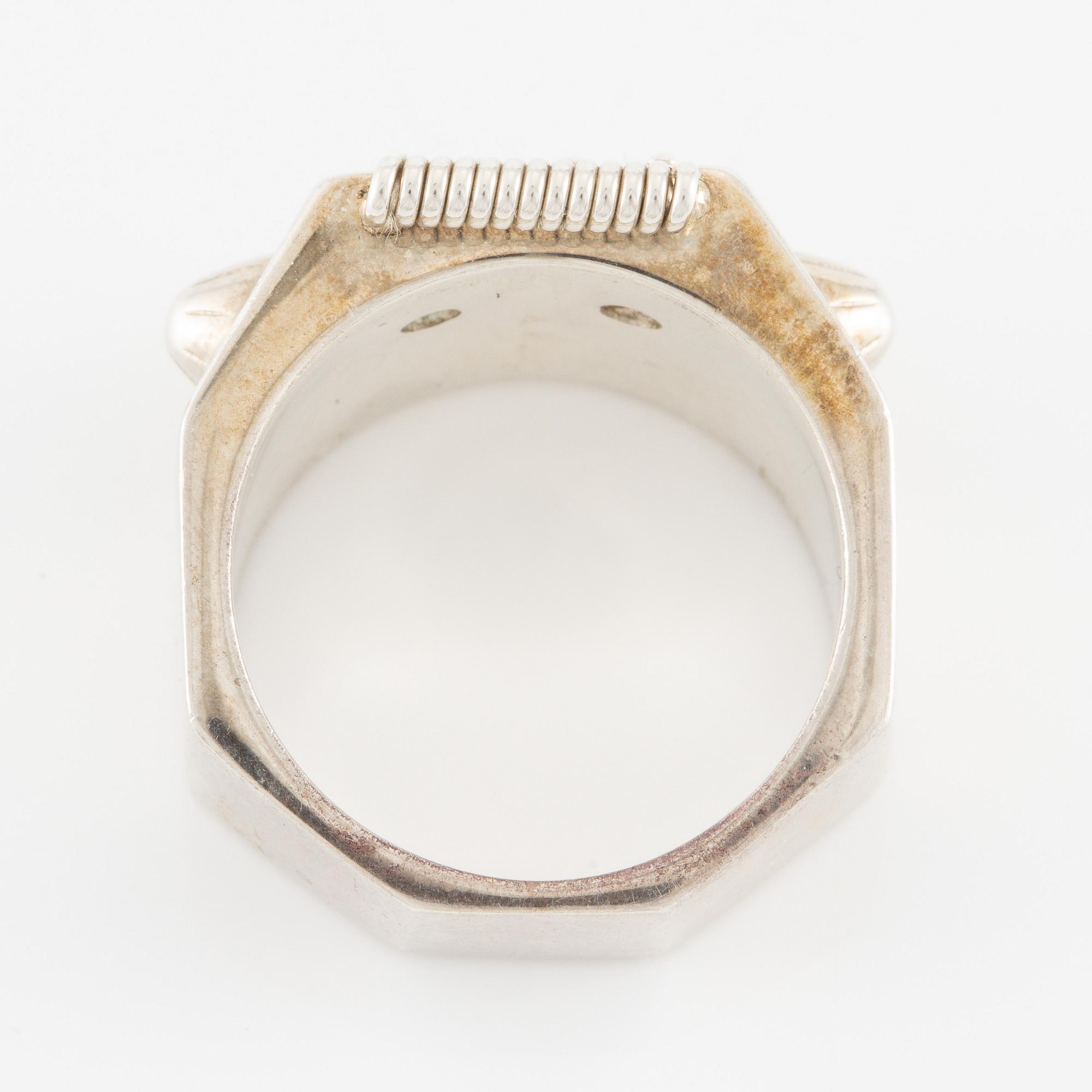 Maria Nilsdotter ring i form av ett robothuvud, sterlingsilver och gröna ögon.