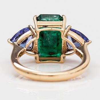 A 14K gold ring with tanzanites and a ca 5.80 ct emerald.