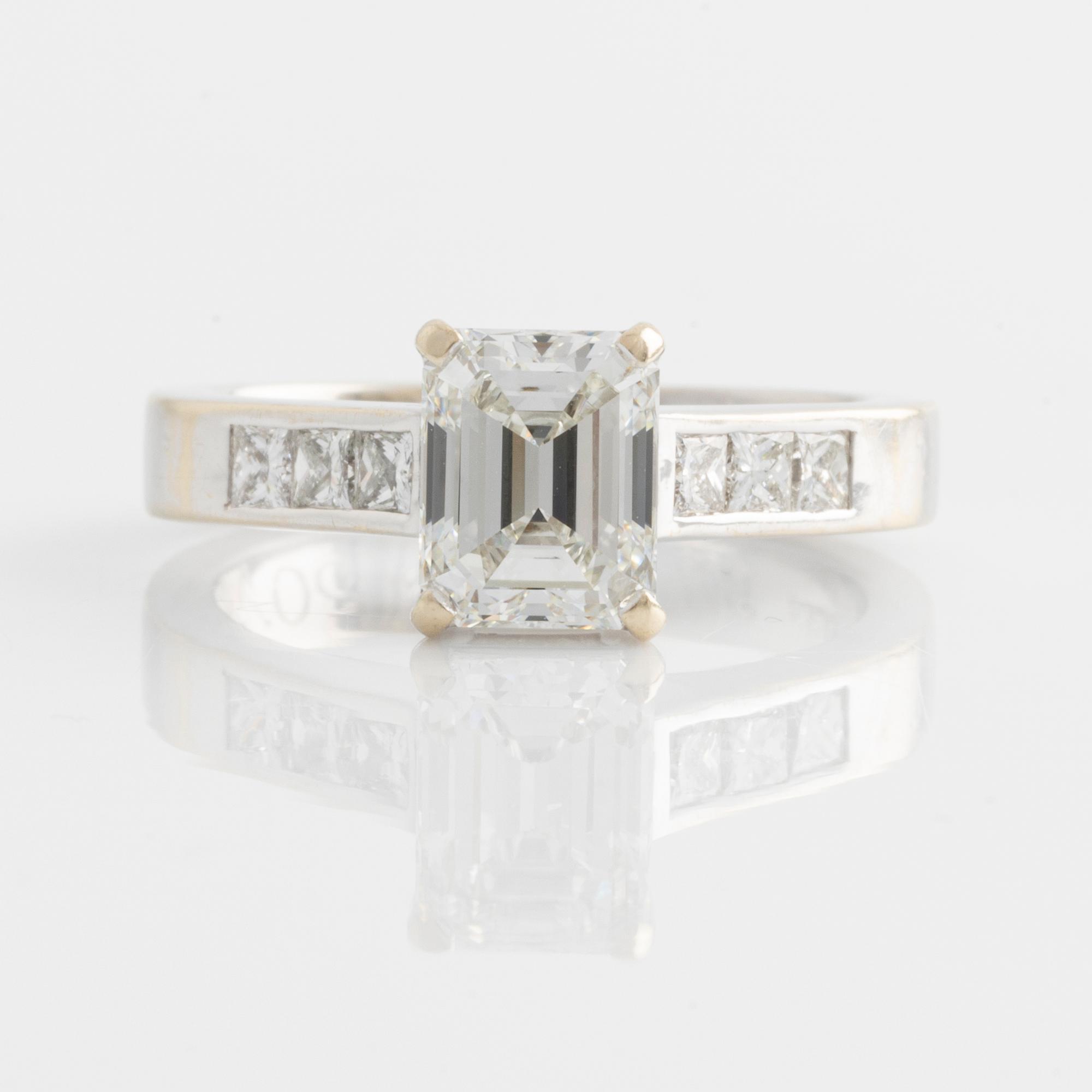 An 18K white gold ring set with an emerald-cut diamond.