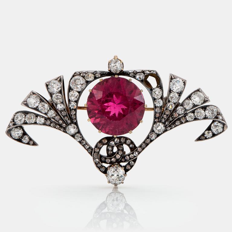 A silver and 14K gold brooch set with a faceted pink tourmaline and old- and rose-cut diamonds.