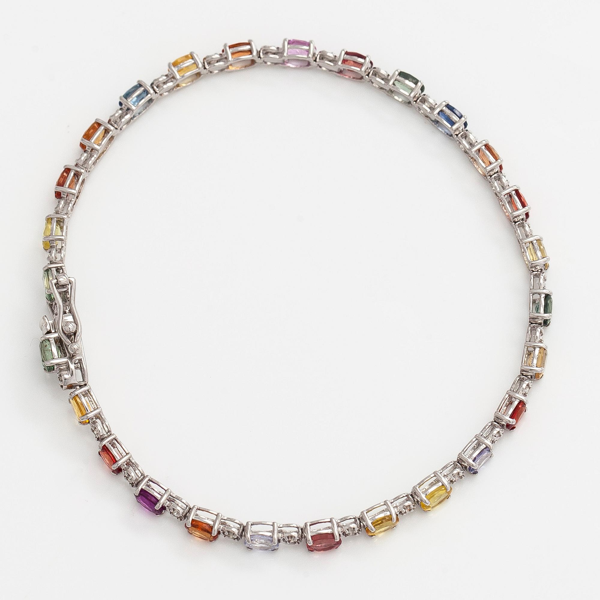 Rannekoru, 18K valkokultaa monivärisillä safiireilla ja timanteilla.