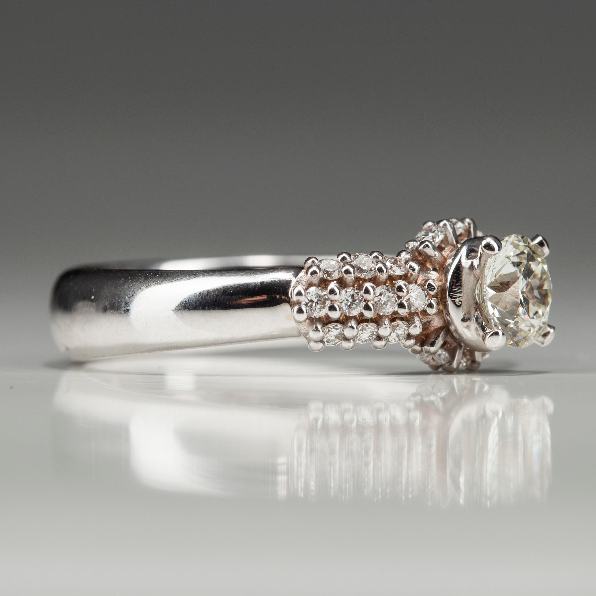 RING, vitguld 18K med diamanter. Mittstenen 0,52 ct L/SI1. 26 små diamanter tot 0,35 ct H/SI1. Intyg.