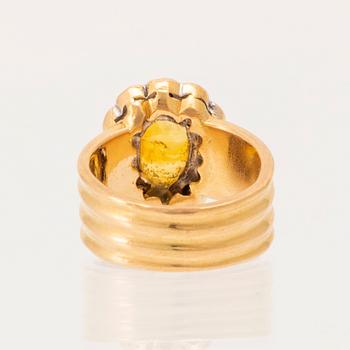 A 22K gold carmosé ring with an oval faceted yellow sapphire and round brilliant-cut diamonds.