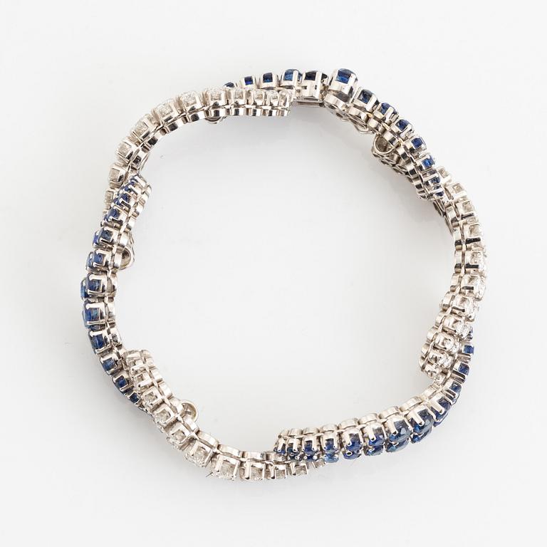 An 18K white gold bracelet set with round brilliant-cut diamonds and sapphires.