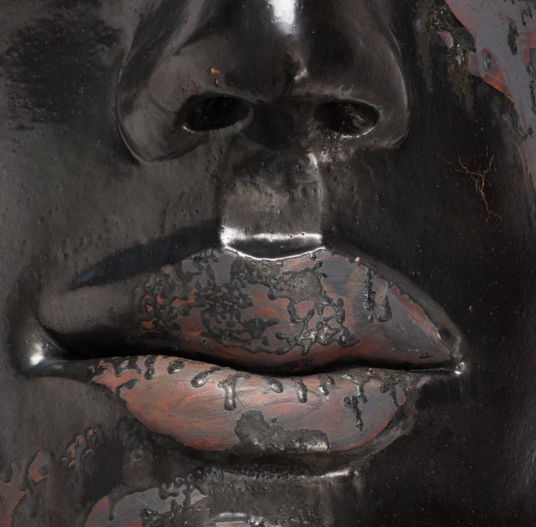 Hertha Hillfon, a black glazed stoneware wall sculpture in two parts of a face and a sky, executed in her own studio, Stockholm 1960s.