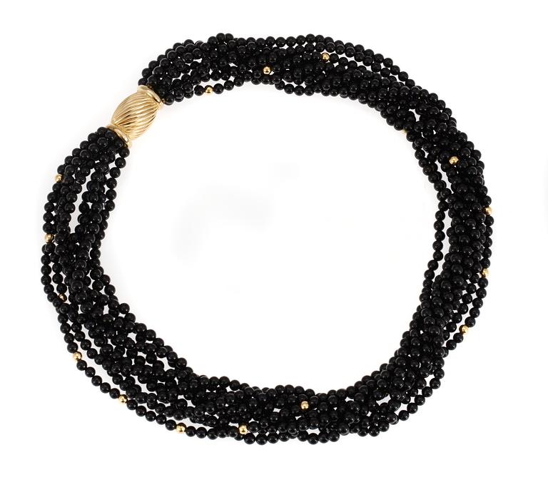 NECKLACE, 9 strands of onyx with gold locket.