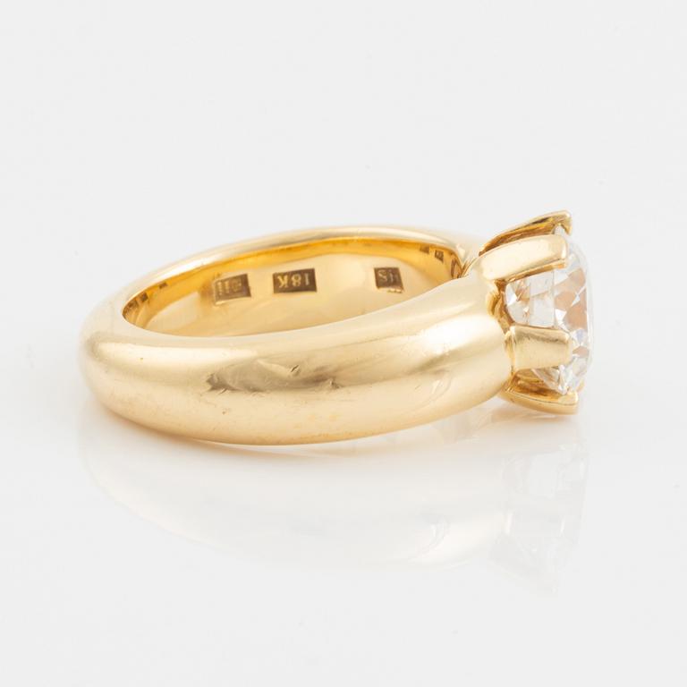 An 18K gold ring set with a round brilliant-cut diamond.