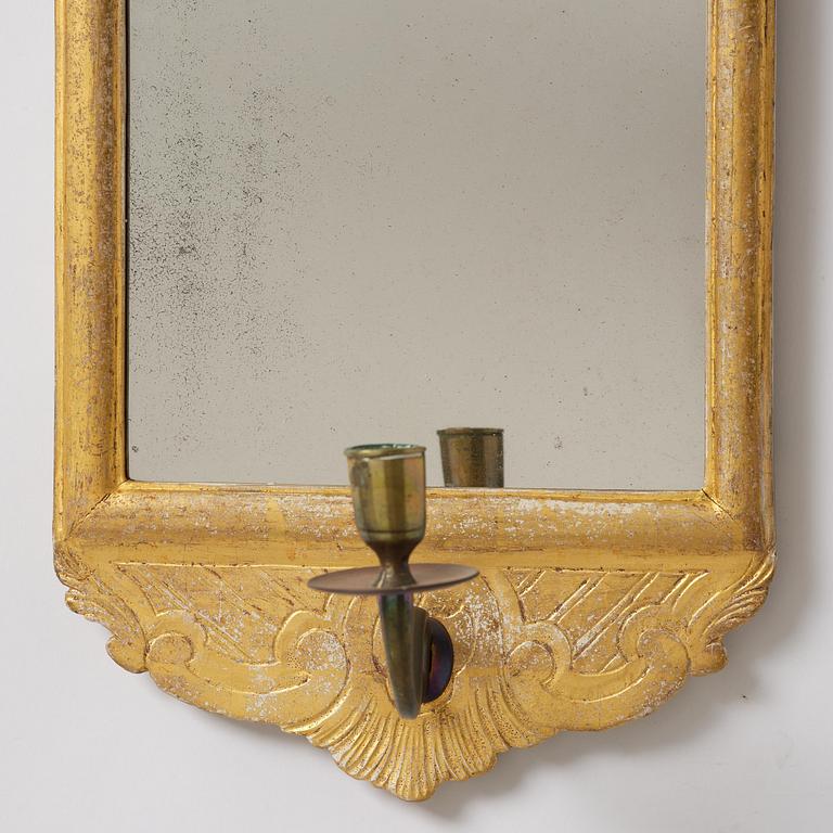A matched pair of rococo giltwood one-branch girandole mirrors, Stockholm, late 18th century.