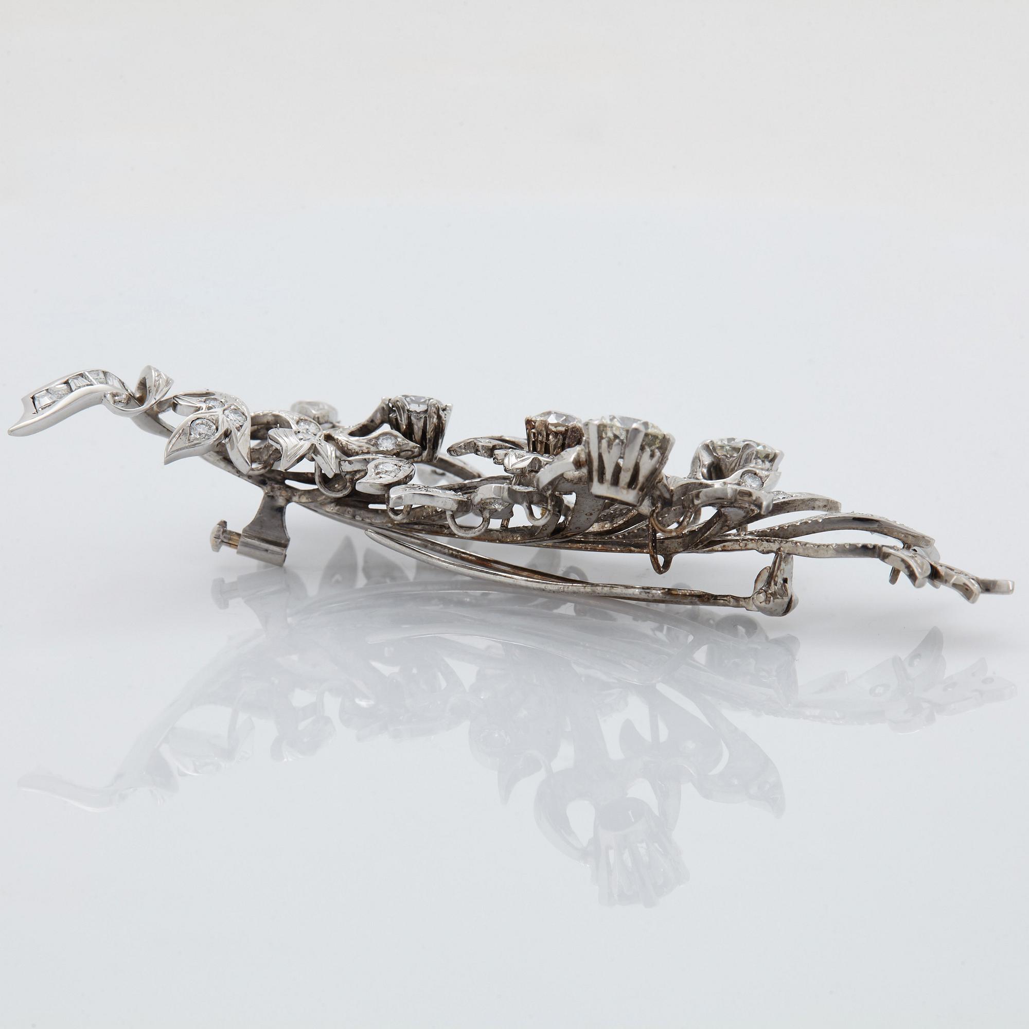 An 18K white gold brooch set with round brilliant-cut diamonds.
