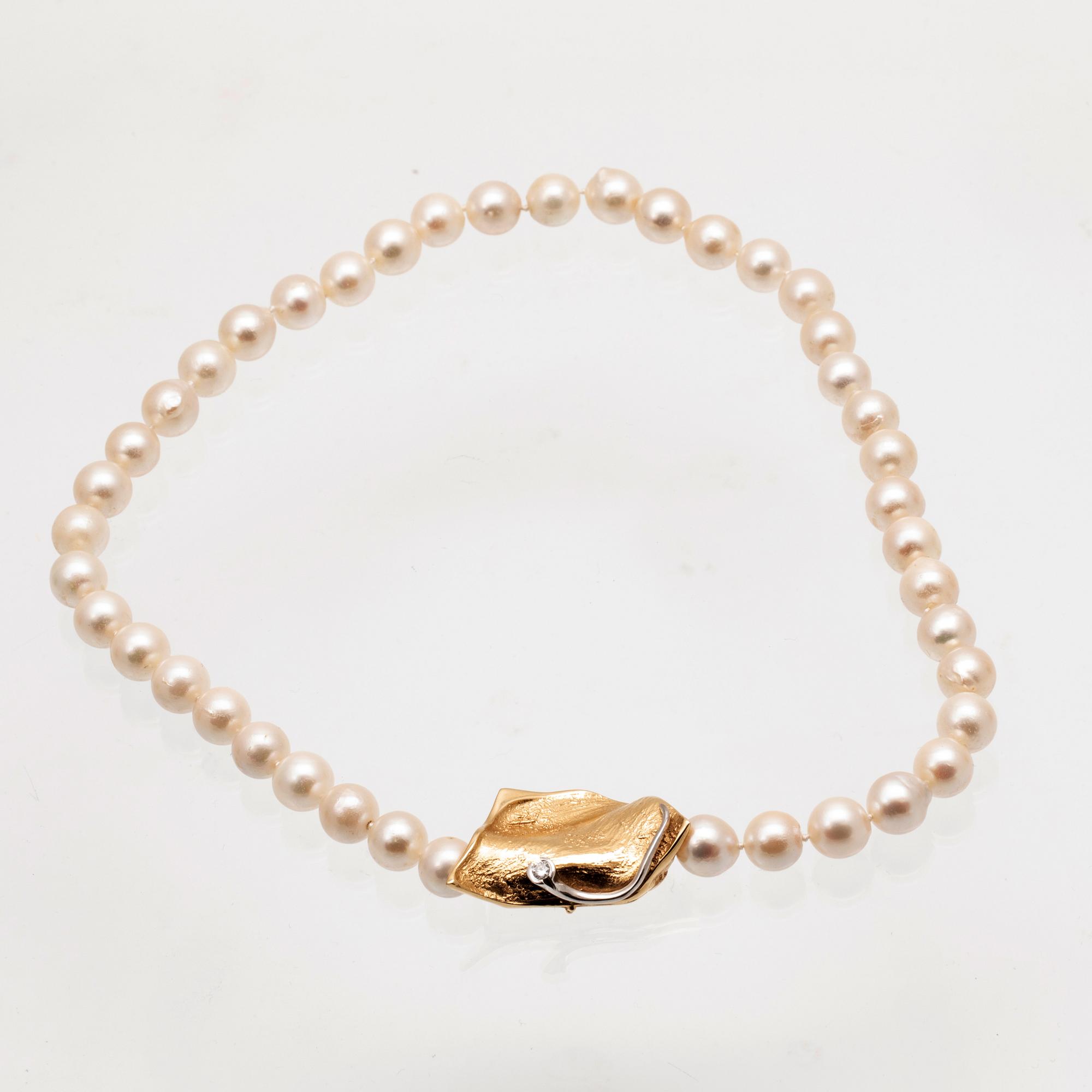 A necklace of cultured pearls, lock in 18K white and red gold set with a round brilliant cut diamond by Ole Lynggaard.