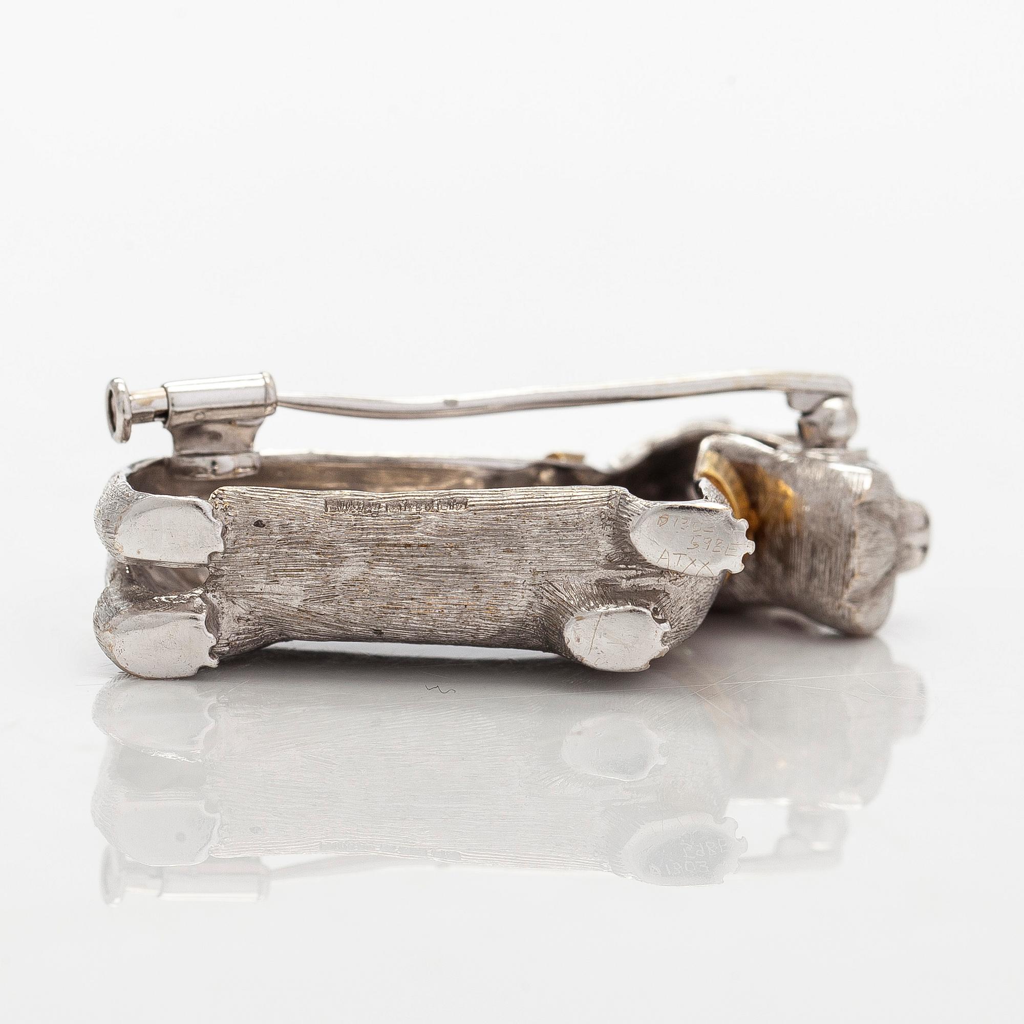 Rintaneula, 18K valkokultaa, sekä granaatteja ja briljanttihiottuja timantteja. BW&Co, Lontoo.