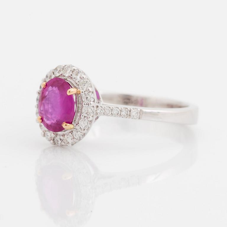 An 18K white gold ring set with a faceted pink sapphire and round brilliant-cut diamonds.