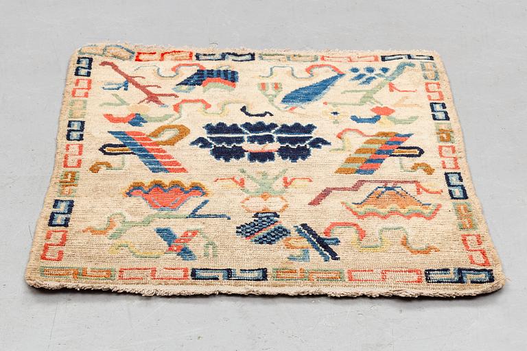 A rug, antique Tibet, ca 71 x 57,5-59 cm (as well as 1,5 cm flat weave at one end).