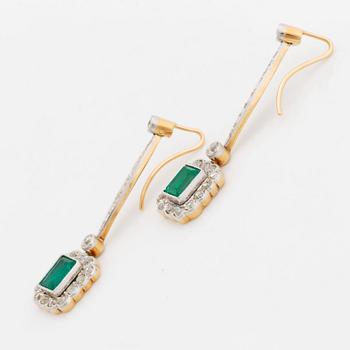 A pair of platinum and gold earrings set with step-cut emeralds and old-cut diamonds.