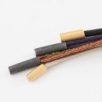 Ole Lynggaard fyra stycken halsband/remmar i textil samt guld och silver.