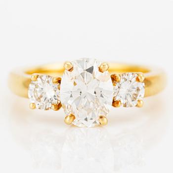 A ring in 18K gold with an oval brilliant-cut diamond and two round brilliant-cut diamonds.