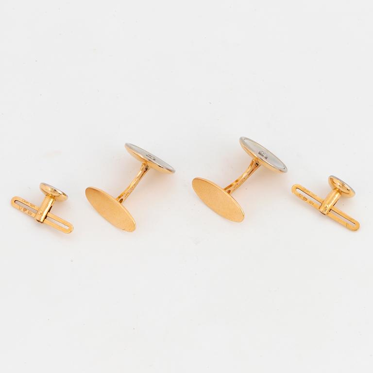 A pair of cufflinks and a pair of shirt buttons.