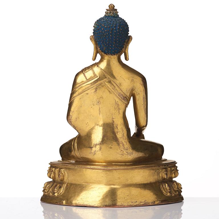 A gilt copper alloy figure of Akhsobya buddha, Tibet, 15th Century.