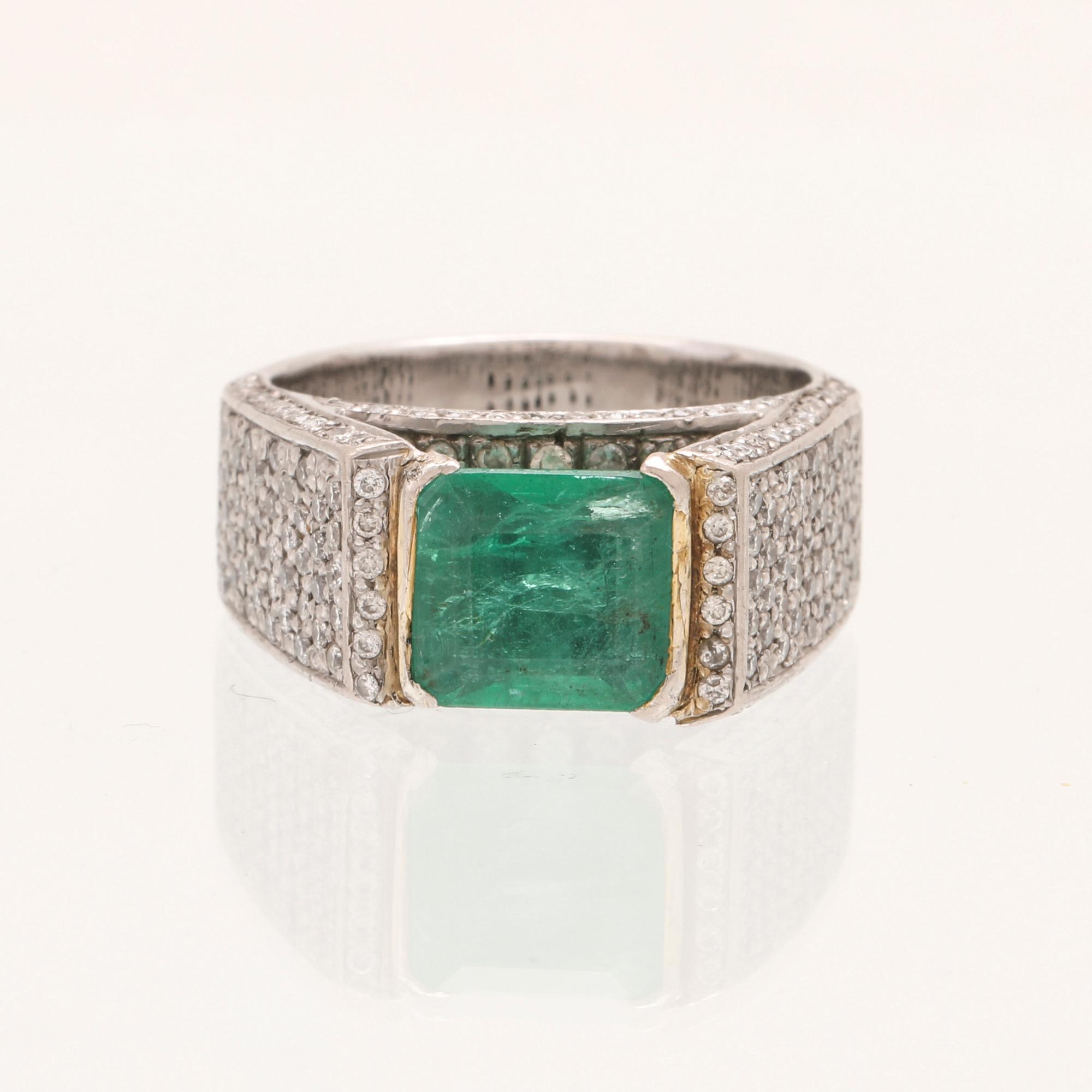 A 9K white gold ring with an emerald and brilliant cut diamonds.