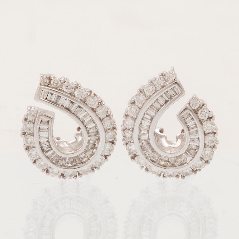 A pair of 18K white gold earrings set with round brilliant-cut and tapered baguette-cut diamonds.